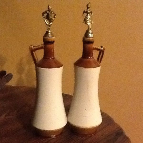 Two porcelain or clay pots sit side by side on a table. White wall in the background.